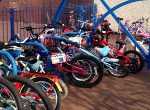 A school bike rack overflowing with bikes and scooters