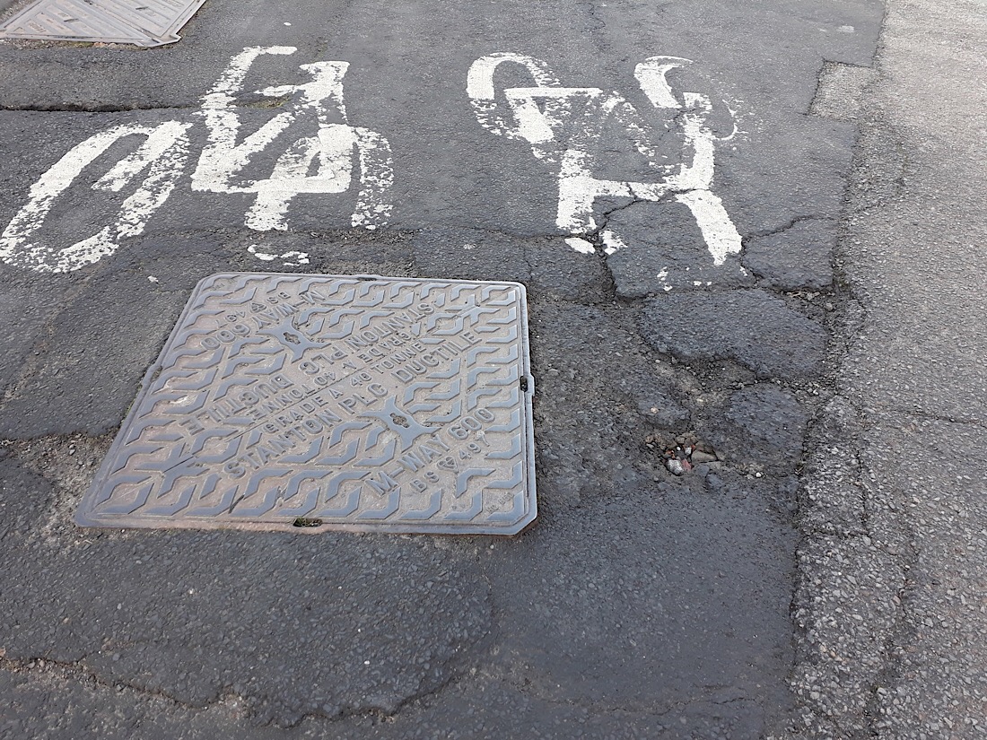 Photo of the cracked and potholed road surface on Alwinton Terrace.